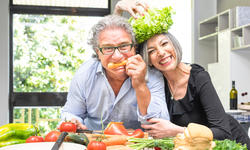 Senior couple having fun in kitchen with healthy f
